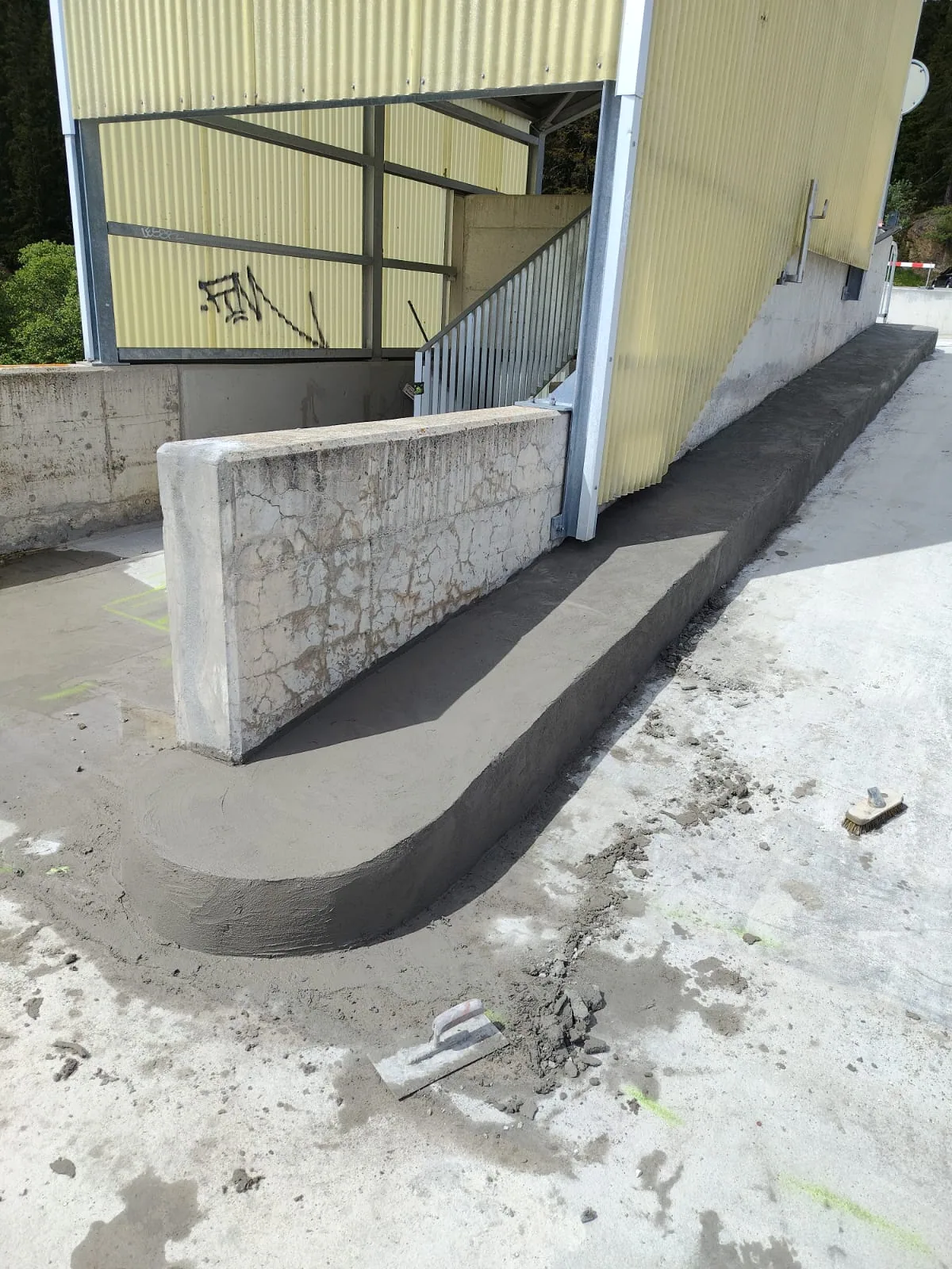 Freshly repaired concrete ramp and edge beside a staircase